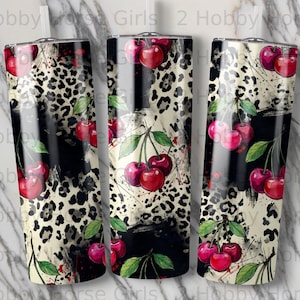 May include: Three stainless steel tumblers with a cherry and leopard print design. The design features red cherries with green leaves against a black and white leopard print background. The tumblers are cylindrical and have a glossy finish.
