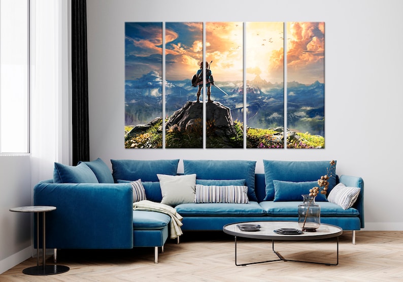 Puede incluir: Una impresi&oacute;n en lienzo de varios paneles que representa a un personaje de videojuego de pie en la cima de una monta&ntilde;a con vistas a un vasto paisaje. El personaje lleva una t&uacute;nica verde y sostiene una espada. El cielo es de un naranja y amarillo vibrantes, con nubes y p&aacute;jaros volando por encima.