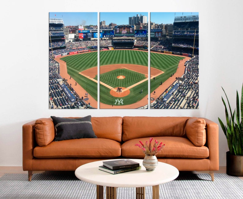 May include: An aerial view of a baseball field with a green grass infield and a brown dirt outfield. The stands are full of fans wearing blue and white clothing. The field is surrounded by a fence and there are several signs visible, including "DELTA" and "CASIO".