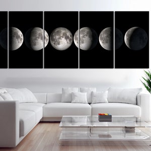 May include: A black and white canvas print of the moon in different phases. The print is divided into eight sections, each showing a different phase of the moon. The print is hanging on a white wall above a white couch and a glass coffee table.