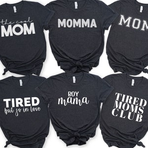May include: Six dark grey t-shirts with white text. The shirts read "the cool MOM", "MOMMA", "MOM", "TIRED but so in love", "BOY mama", and "TIRED MOMS CLUB".