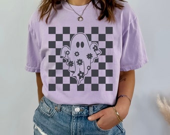 May include: A lavender t-shirt with a black and white chequered pattern and a grey ghost with flowers on it.