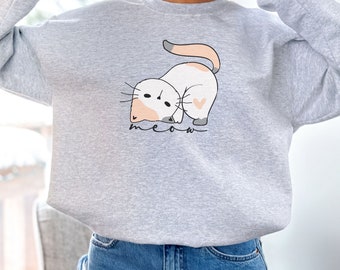 Peut inclure: Un sweat-shirt gris avec un motif de chat de dessin animé et le mot "meow" imprimé sur le devant.