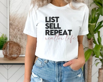 Op de afbeelding: Wit T-shirt met zwarte tekst die "List Sell Repeat realtor life" luidt. De tekst "realtor life" is roze.