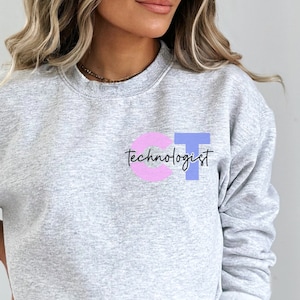Könnte beinhalten: Grauer Pullover mit den Buchstaben CT in Rosa und Blau und dem Text "technologist" in Schwarz.
