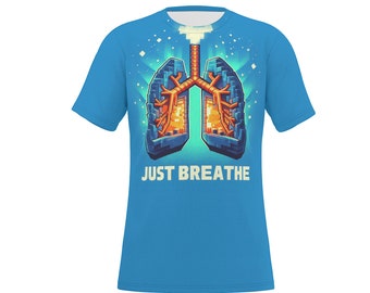 May include: A light blue t-shirt featuring a pixelated illustration of lungs with orange and blue tones. The text "JUST BREATHE" is printed in white below the graphic. The shirt has short sleeves and a crew neck.