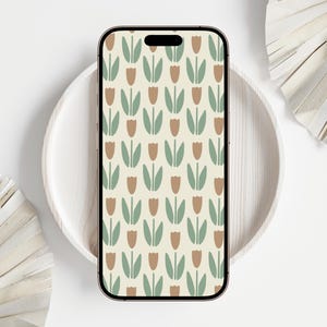 Könnte beinhalten: Ein Smartphone zeigt ein sich wiederholendes Muster stilisierter Tulpen in Braun-, Grün- und Cremetönen. Das Telefon liegt auf einem weißen, runden Tablett, mit dekorativen Papierfächern im Hintergrund. Die Gesamtästhetik ist minimalistisch und von der Natur inspiriert.