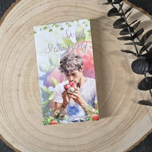 May include: A book cover with a watercolor illustration of a person smelling a bunch of strawberries. The text on the cover reads "Sweet Strawberry".