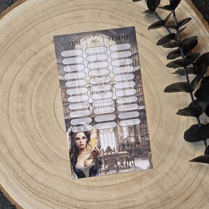 May include: A sticker sheet with a vintage design featuring a woman holding a rose, with the text "DATUM" and "SUMME". The sheet has multiple oval spaces for writing. The background shows a library scene.