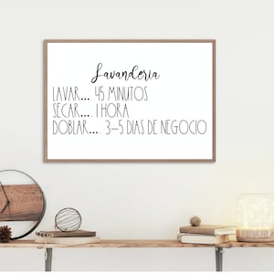 May include: A framed print with a white background and black text that reads "Lavanderia" and lists the time it takes to wash, dry, and fold laundry in Spanish. The text reads "Lavar... 45 Minutos, Secar... 1 Hora, Doblar... 3-5 Dias de Negocio".