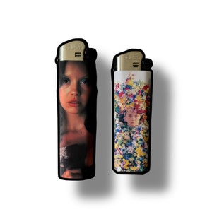 May include: Two lighters with different images. The first lighter has a picture of a woman with long dark hair. The second lighter has a picture of a woman with a floral crown.