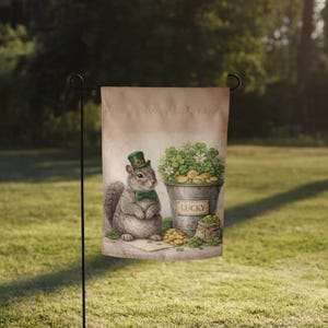 May include: A garden flag featuring a watercolor illustration of a squirrel wearing a green bow tie and top hat. A metal bucket filled with gold coins and shamrocks is next to the squirrel. The word "LUCKY" is on the bucket.