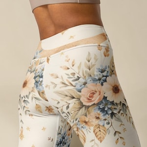 May include: High-waisted leggings featuring a white base color with a botanical print of soft peach roses, light blue flowers, and tan foliage. The design includes small gold star accents scattered throughout the floral pattern on the fabric.