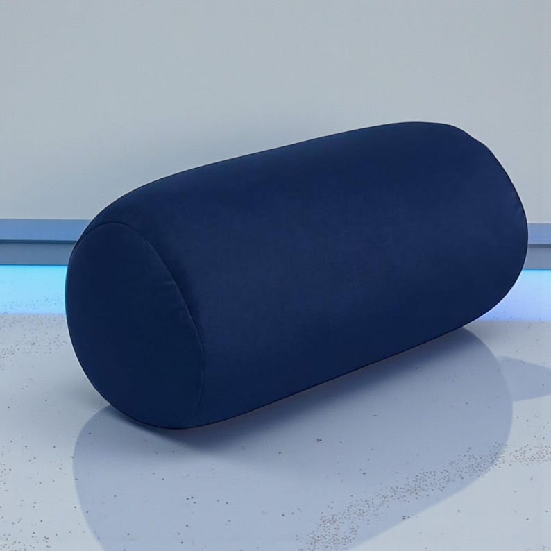 May include: A navy blue bolster pillow with rounded ends. The cylindrical pillow is made of a soft, velvety fabric. The pillow is designed for comfort and support.