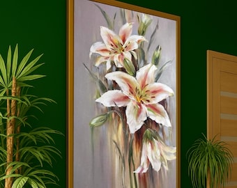 Può includere: Dipinto incorniciato di gigli bianchi con accenti rosa. Lo sfondo è grigio chiaro, con foglie e boccioli verdi. La cornice dorata aggiunge eleganza all'opera botanica. Il dipinto è appeso a una parete verde scuro.