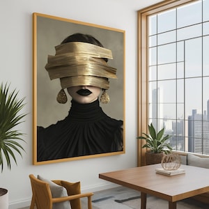 Op de afbeelding: Een ingelijste kunstdruk met een vrouw met goudkleurige platen die haar ogen bedekken. Ze draagt een zwarte coltrui, zwarte lippenstift en gouden druppelvormige oorbellen. Het kunstwerk hangt in een kamer met een houten tafel en een groot raam.