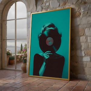 May include: Framed art print featuring a person holding a vinyl record in front of their face. The artwork has a teal background and a gold frame. The person is wearing a black top. The image is set against a brick wall and a window.