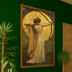Puede incluir: Una impresión artística enmarcada representa a una mujer con un vestido blanco que está tensando un arco. La obra presenta un halo dorado y un arco oscuro sobre un fondo de tonos verdes y dorados. El marco es de color dorado cálido.