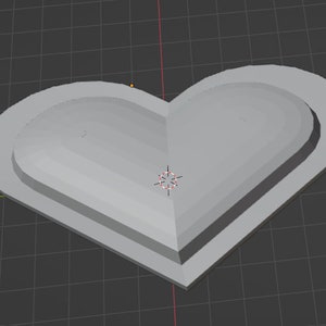 May include: A gray heart-shaped object with wings on either side. The heart is three-dimensional and has a slightly raised edge.