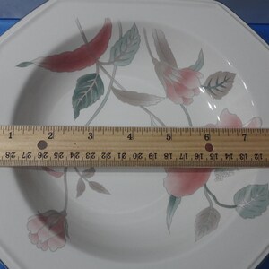 May include: White octagonal ceramic dinner plate with a floral design featuring pink and red flowers, green leaves, and a brown stem. The plate measures approximately 8 inches in diameter.