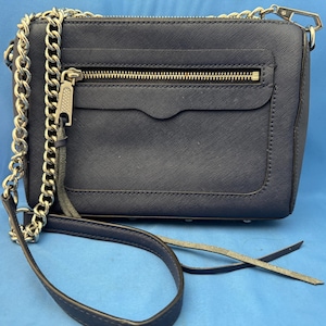 Puede incluir: Bolso bandolera azul marino con cadena plateada y cierre de cremallera. El bolso tiene una superficie texturizada y un peque&ntilde;o bolsillo delantero. La correa es una combinaci&oacute;n de cadena y cuero.
