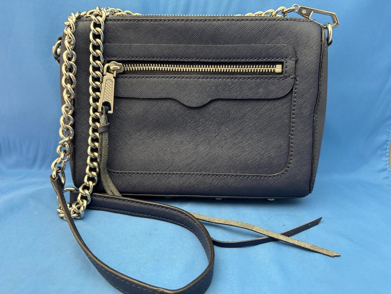 Puede incluir: Bolso bandolera azul marino con cadena plateada y cierre de cremallera. El bolso tiene una superficie texturizada y un peque&ntilde;o bolsillo delantero. La correa es una combinaci&oacute;n de cadena y cuero.