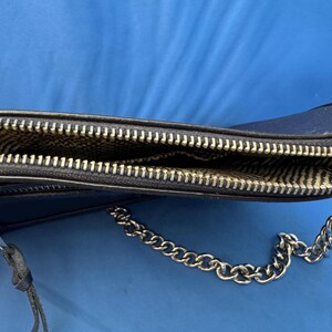 Puede incluir: Un bolso bandolera azul marino con una cadena plateada. El bolso tiene un cierre de cremallera y un forro interior estampado. La cremallera es plateada y el bolso est&aacute; hecho de un material liso.