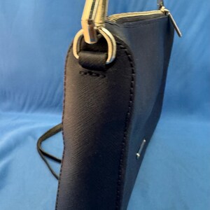Puede incluir: Un bolso bandolera azul marino con una cadena plateada y una correa de cuero negro. El bolso tiene cierre de cremallera y herrajes plateados. El bolso est&aacute; hecho de un material texturizado.
