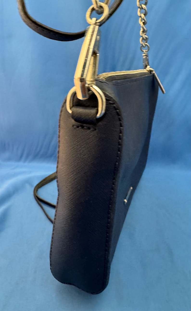 Puede incluir: Un bolso bandolera azul marino con una cadena plateada y una correa de cuero negro. El bolso tiene cierre de cremallera y herrajes plateados. El bolso est&aacute; hecho de un material texturizado.