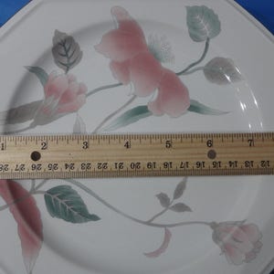 May include: Octagonal white ceramic dinner plate with a floral design featuring pink and green flowers. The plate measures 8 inches in diameter.