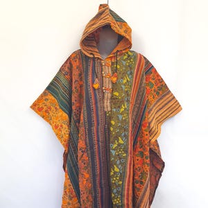 May include: A colorful, hooded poncho with a vibrant mix of orange, green, and blue stripes and patterns. The poncho features a hood, wooden toggle closures, and fringe along the bottom. The textile design includes floral and geometric motifs.