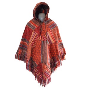 Könnte beinhalten: Ein farbenfroher Kapuzenponcho mit einem geometrischen Muster in Rot-, Orange-, Gelb-, Blau- und Grüntönen. Der Poncho hat einen Fransenrand und eine Kapuze mit Kordelzug.