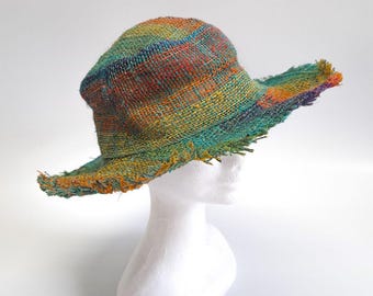 May include: A colorful, woven hat with a wide brim and frayed edges. The hat is made of a natural fiber and has a rainbow pattern.