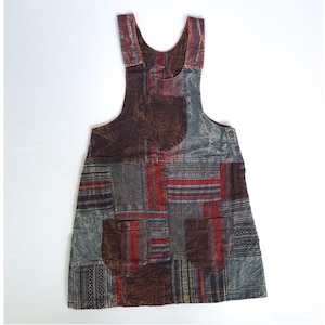 May include: A brown and gray patchwork overall dress with a red and white striped pattern. The dress has two pockets and adjustable straps.