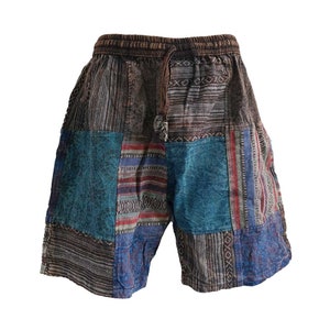 May include: Patchwork shorts with a drawstring waist. The shorts are made from a variety of fabrics in shades of brown, blue and red. The fabric has a woven pattern.