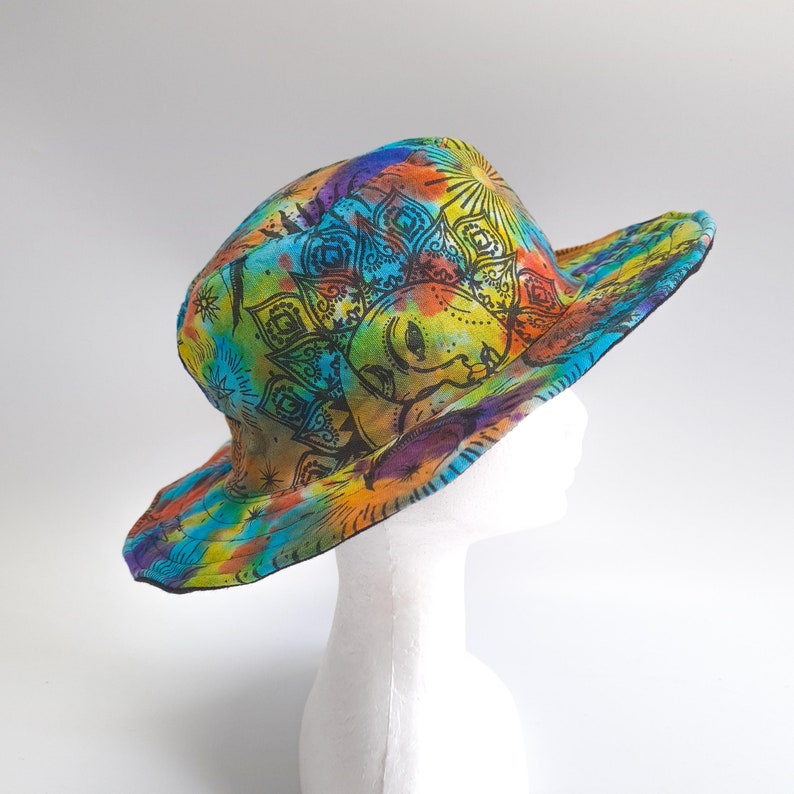 May include: A colorful sun hat with a tie-dye pattern and a black mandala design. The hat features a sun with a face and a floral design.
