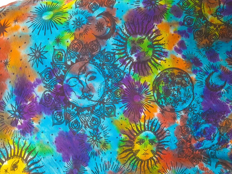 May include: A colorful tie-dye fabric with a repeating pattern of suns, moons, and stars. The fabric is a mix of blue, purple, orange, yellow, and green.
