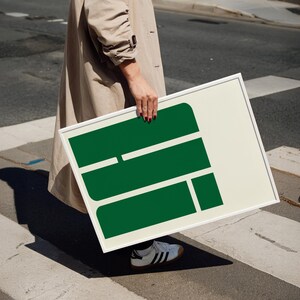 A person is standing on a street, holding a large green sign with a white border.