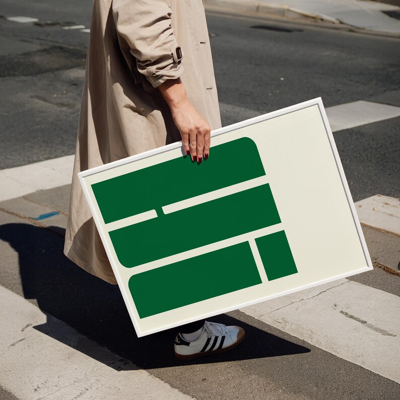 A person is standing on a street, holding a large green sign with a white border.