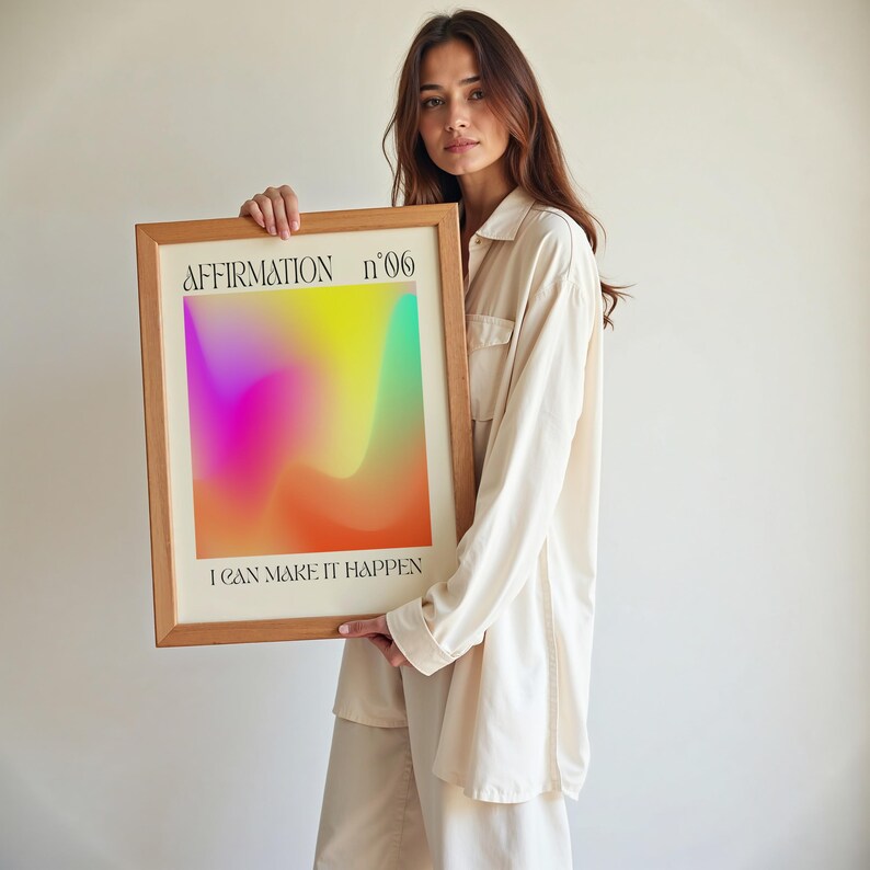 a woman holding up a framed poster with a rainbow background