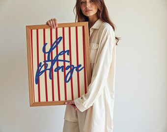 May include: A framed print with red and white stripes and the text "La Plage" in blue lettering.