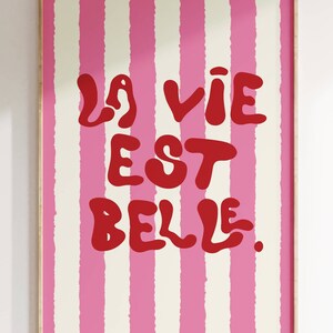 May include: A pink and white striped poster with the text "La vie est belle." in red.