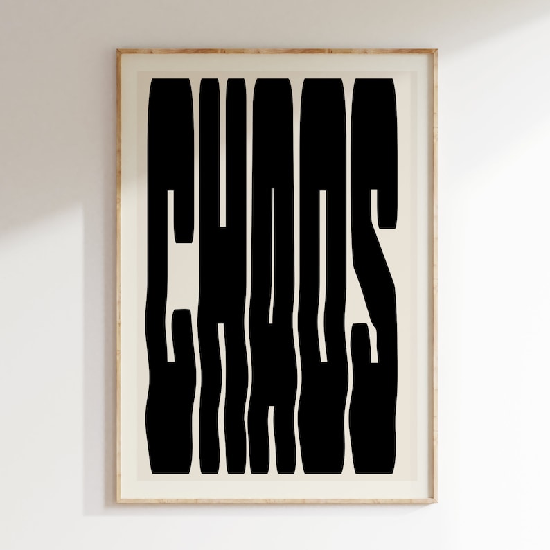 May include: A black and white print with the word "CHAOS" in a bold, stylized font. The print is framed in a light wood frame.