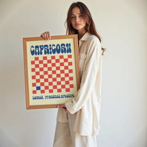 a woman holding a framed picture of a checkered board