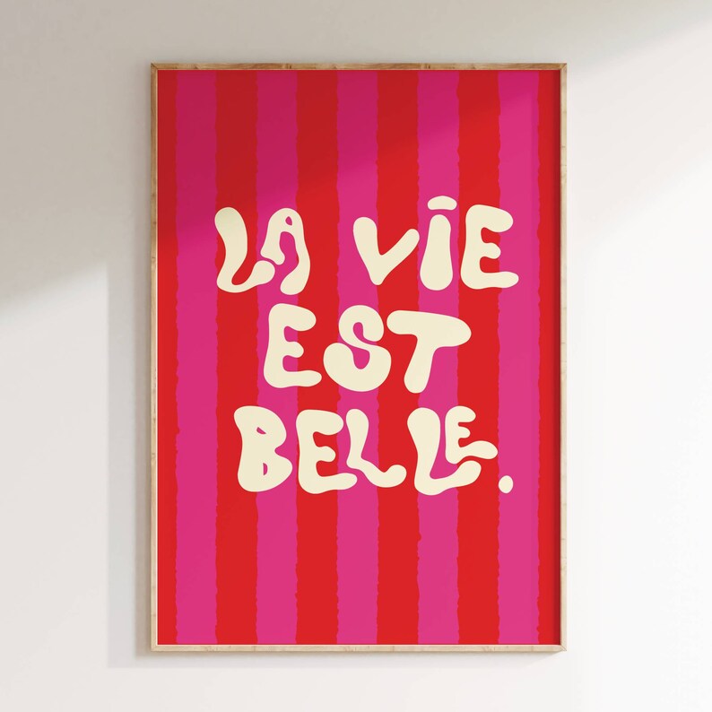 May include: A pink and red striped poster with the text "La vie est belle." in white.