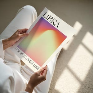 May include: A white card with the word "LIBRA" in black text and a gradient background of pink, orange, yellow, and green. The text "SENSIBLE LOVING, LOYAL" is printed in black at the bottom of the card.