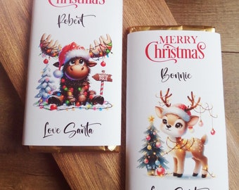 May include: Two personalised Christmas chocolate bars with festive illustrations. One features a moose with lights and the text "Merry Christmas Robert Love Santa". The other features a reindeer with lights and the text "Merry Christmas Bonnie Love Santa".