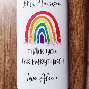 Op de afbeelding: Witte chocoladereepverpakking met een regenboogontwerp en de tekst "Mr Harrison, Bedankt voor alles! Love Alex x". De regenboog heeft rode, oranje, gele, groene, blauwe en paarse bogen met roze hartjes.