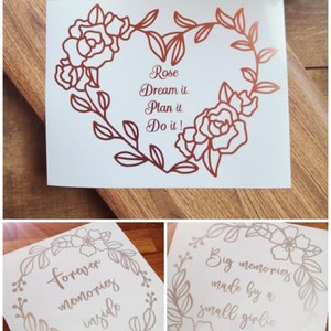 May include: Three floral designs with inspirational quotes. The first design features a rose with the text "Rose Dream it. Plan it. Do it!" The second design features a floral wreath with the text "Forever memories inside". The third design features a floral wreath with the text "Big memories made by a small girlie".