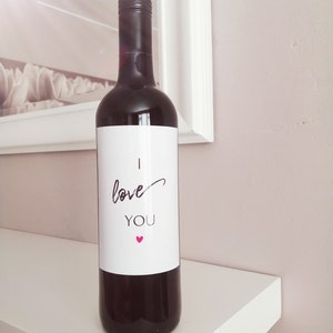 Pu&ograve; includere: Una bottiglia di vino rosso con un'etichetta bianca che dice "Ti amo" con un piccolo cuore rosa.